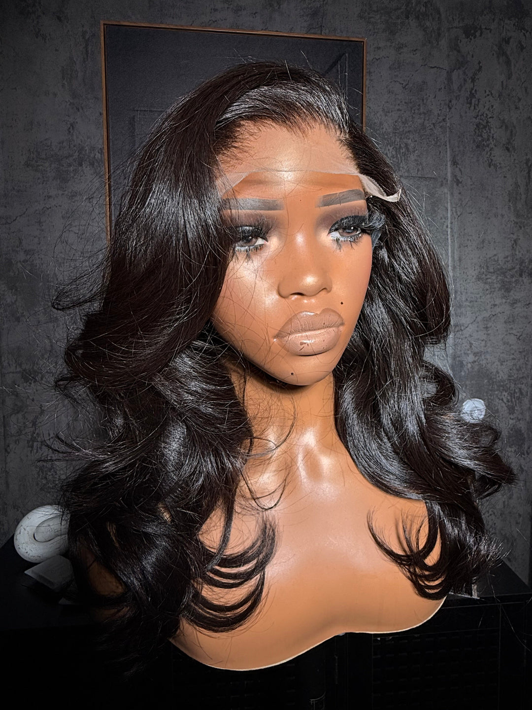 Mannequin head with a black wig on a dark surface