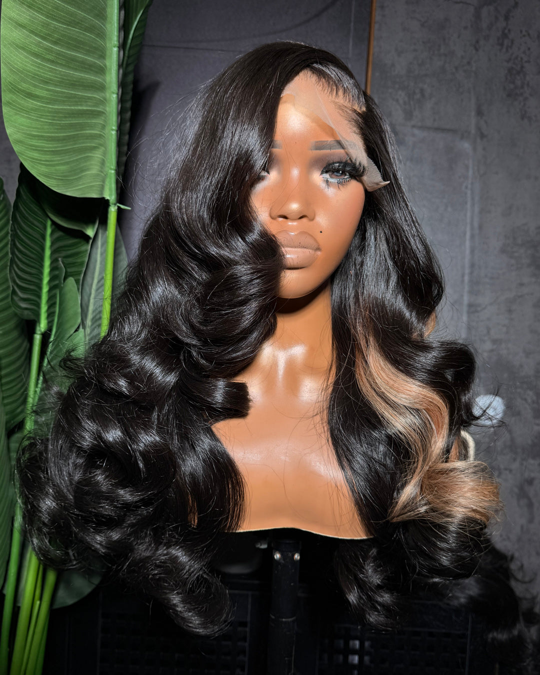Mannequin head with a black and blonde wig on a dark background